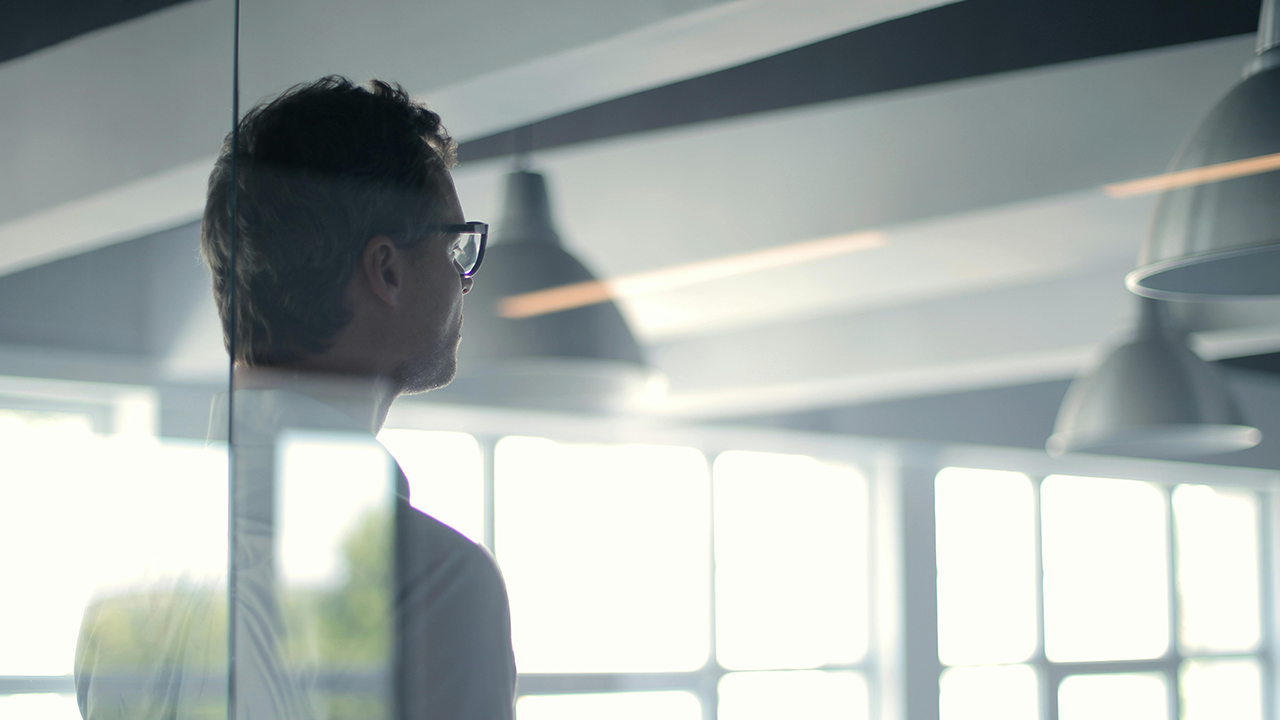 An image of someone, likely a Toronto real estate agent, taken from the back behind some corporate glass wall room dividers.